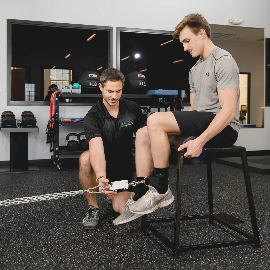 two men in a rehab clinic with one male doing leg exercises