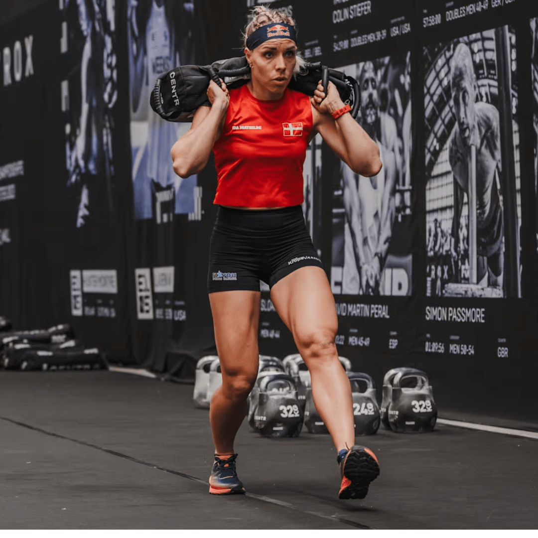 athletic female with sandbag in hyrox gym