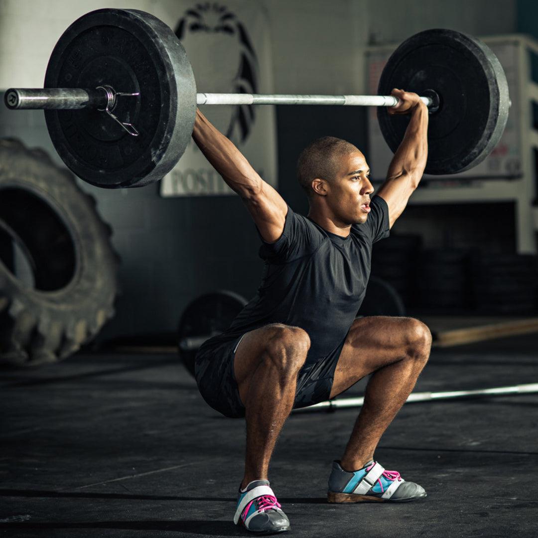 Young Attractive Male Lifting Barbell and Squatting