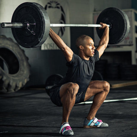 Young Attractive Male Lifting Barbell and Squatting